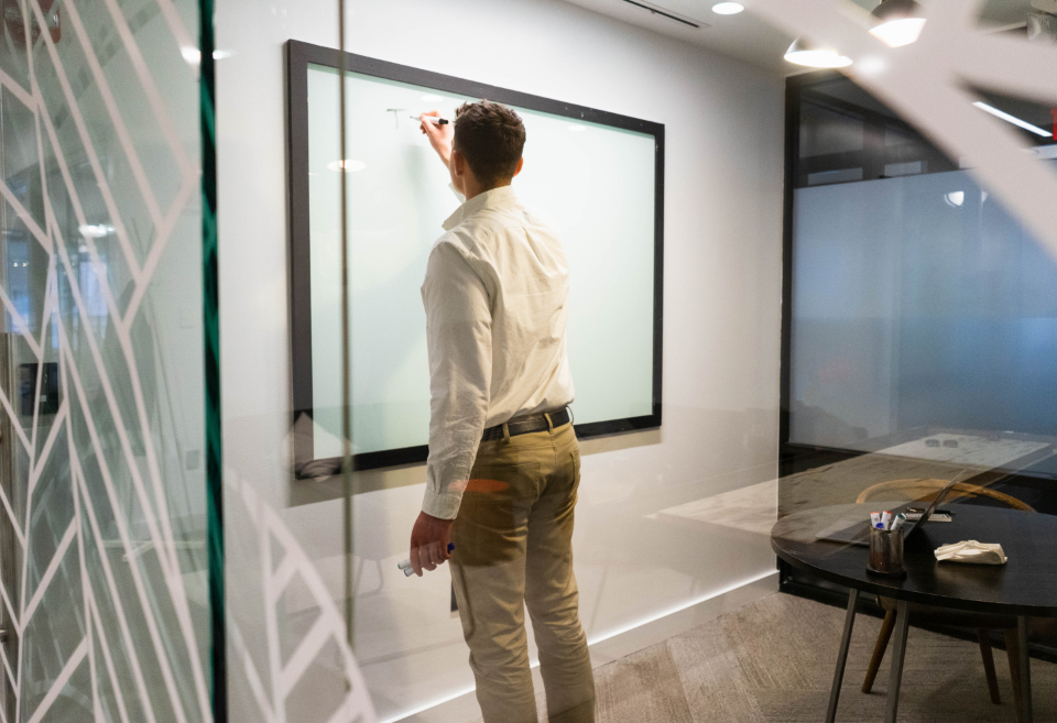 Executive writing on a glass wall during a boardroom session
