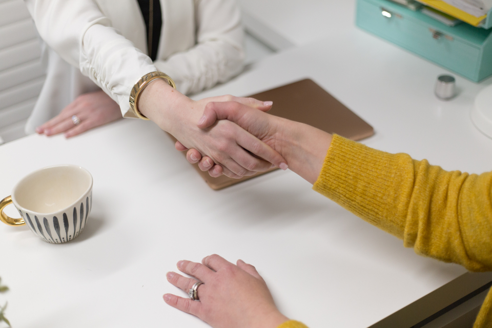 Two people shaking hands over a signed agreement